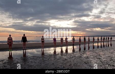 Portobello, Edimburgo, Scozia, Regno Unito. 20th Mar 2020. Temperatura 0 gradi centigradi come il WanderWoman Scozia riflettere su dover mantenere la loro distanza sociale, celebrare primavera Equinox con una nuotata all'alba. Durante gli Equinozi l'inclinazione della Terra (rispetto al Sole) è di 0° e a causa della sua durata del giorno e della notte è quasi uguale nel giorno Equinozio, cioè 12 ore Foto Stock