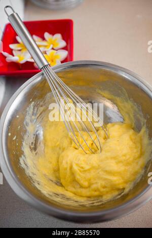 Montare la crema gialla con una frusta da vicino Foto Stock