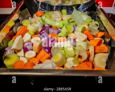 36 porri, cipolla rossa, carote e patate in un vassoio pronto per la tostatura Foto Stock