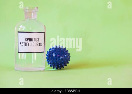 Etanolo in una bottiglia sul tavolo con di microscopio virus primo piano, Coronavirus Concept Tablet nelle dita della mano Foto Stock