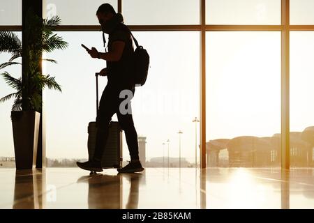 viaggiatore a piedi con una valigia, passeggero per un tour nel terminal dell'aeroporto per viaggi in aereo Foto Stock