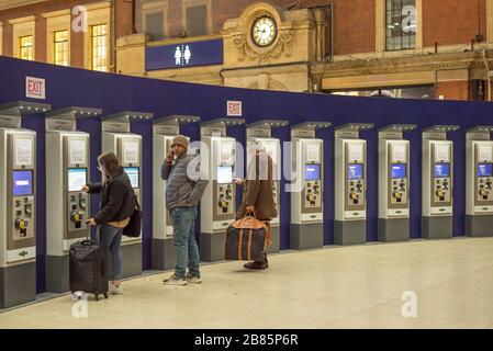 Passeggeri ferroviari che acquistano biglietti ferroviari presso macchine automatiche, stazione ferroviaria Victoria, Londra UK, di notte. Trasporto a Londra, viaggio in treno, biglietteria. Foto Stock