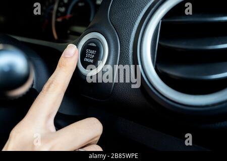 Utilizzando il pulsante per avviare e arrestare il motore, la donna preme il dito verso il basso. Il comfort nella guida di un'auto è qualcosa che tutti vogliono. Foto Stock