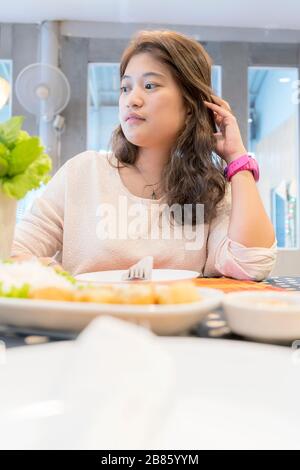 Donne asiatiche che mangiano cibo, seduti in un ristorante, scena frontale con il cibo messo. Foto Stock