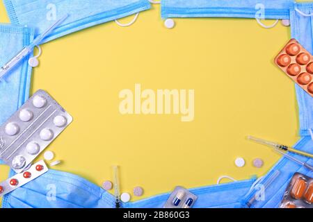 Pillole di medicina farmaceutica assortite, maschere protettive e capsule su sfondo giallo Foto Stock