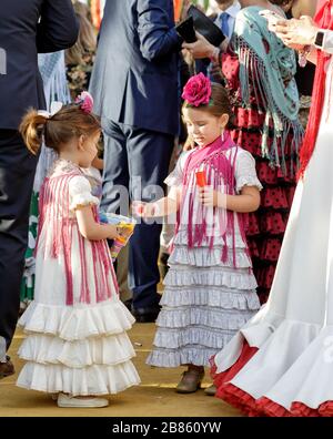 Bambine vestite con costumi tradizionali che giocano con bolle di sapone alla Fiera di aprile (Feria de Abril), Siviglia Foto Stock