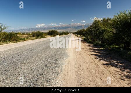 Strada asfaltata lungo la riva meridionale del lago Issyk-Kul in Kirghizistan. Foto Stock