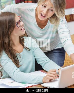 ragazza teen sorridente che fa i compiti con un insegnante biondo Foto Stock