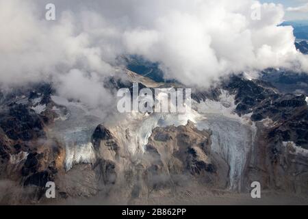 Vista panoramica aerea della catena montuosa e dei ghiacciai attraverso le nuvole, Alaska Range, Alaska Foto Stock