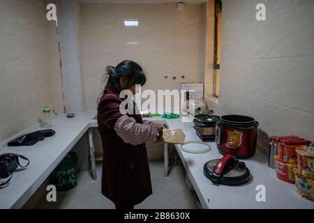 (200320) -- KUNMING, 20 marzo 2020 (Xinhua) -- Villager Wang Daxiang si prepara a fare il pasto nella sua nuova casa nella zona di reinsediamento Maojiawan nella Contea di Ludian, provincia di Yunnan della Cina sudoccidentale, 15 marzo 2020. Immerso nelle montagne della provincia di Yunnan della Cina sudoccidentale, il villaggio di Luoqiu ospita solo decine di famiglie sparse nella valle di montagna. Il Villager Yan Fugao e sua moglie Wang Daxiang vivono qui da più di 20 anni. Il duro ambiente montano qui ha gravemente limitato le attività economiche della popolazione locale e ha causato alcuni di loro poveri. La famiglia di Yan Fugao è tra loro Foto Stock