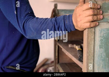 Carpentiere riparazione armadi in legno vintage, uomo costruire una casa e lavorare con martello e legno. Foto Stock