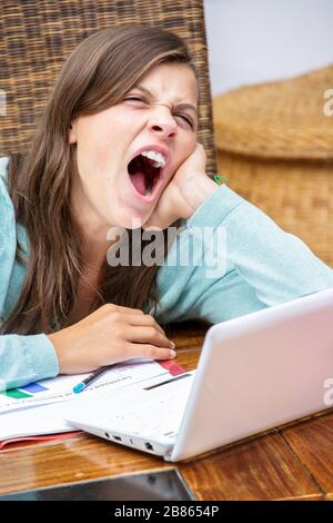 bella ragazza stanca studente che fa il suo lavoro mentre yawning Foto Stock