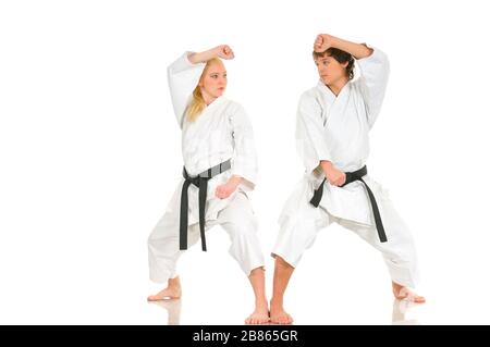 La giovane bionda forte e l'impudente ragazzo di karate sono impegnati nell'allenamento in un kimono su sfondo bianco. Giovane coppia di atleti professionisti. Foto Stock