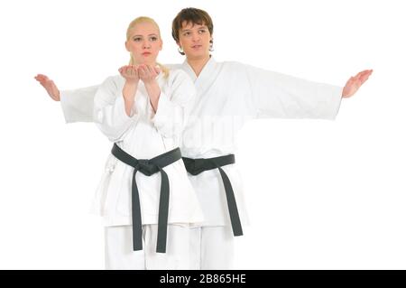 La giovane bionda forte e l'impudente ragazzo di karate sono impegnati nell'allenamento in un kimono su sfondo bianco. Giovane coppia di atleti professionisti. Foto Stock