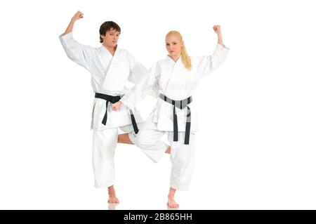 La giovane bionda forte e l'impudente ragazzo di karate sono impegnati nell'allenamento in un kimono su sfondo bianco. Giovane coppia di atleti professionisti. Foto Stock