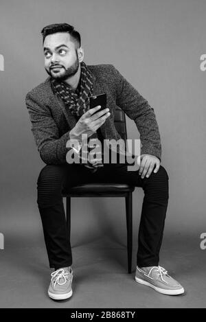 Giovani barbuto imprenditore indiano contro lo sfondo grigio Foto Stock