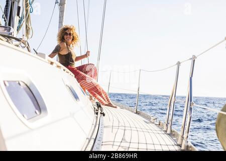 Felice donna godere viaggio in barca a vela sedersi sulla barca con l'oceano intorno - stile di vita di vacanza di lusso per le persone ricche - bello curly bionda fe Foto Stock