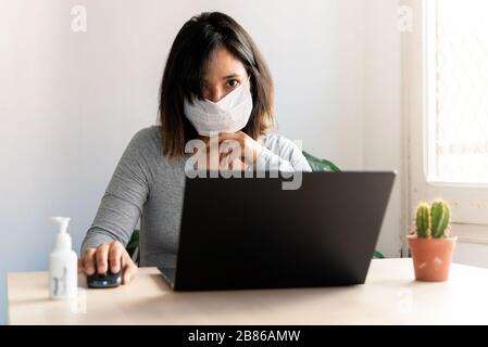 giovane donna che indossa la maschera facciale protettiva e con il lavoro di igienizzazione delle mani dall'ufficio domestico a causa dell'epidemia del virus della corona, la quarantena è una misura prende a s. Foto Stock