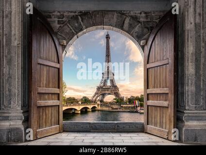 Grande porta di legno aperta con la Torre Eiffel sul Fiume Senna al tramonto a Parigi, Francia Foto Stock