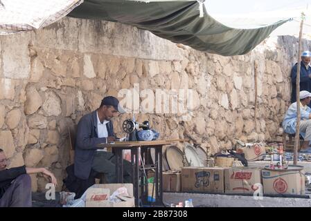 Essaouira, Marocco - Settembre 2017: Un sarto lavora e sega sotto una tettoia al mercato berbero locale - grandangolo Foto Stock