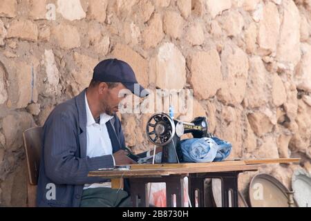 Essaouira, Marocco - Settembre 2017: Un sarto lavora e sega sotto una tettoia al mercato berbero locale - angolo stretto Foto Stock