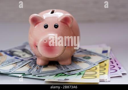 piggy banca cento dollari fatture e banconote in euro di diverse denominazioni Foto Stock