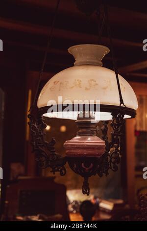 Lampada a sospensione in stile retrò a forma di lampada kerosene vintage con paralume in vetro bianco opaco globo su sfondo scuro sfocato. Illuminazione pensile equipotenziale Foto Stock