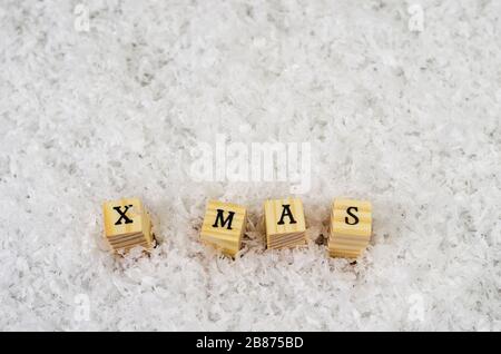 x mas parola fatta di lettere su cubetti di legno su uno sfondo di neve 2 Foto Stock