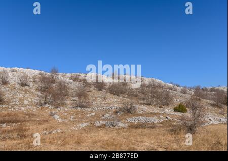 vecchio muro di pietra rustico rimane nel terreno selvaggio delle montagne Foto Stock