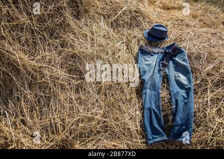 jeans blu su paglia asciutta in concetto cowboy con giorno di sole sul sito di campagna Foto Stock