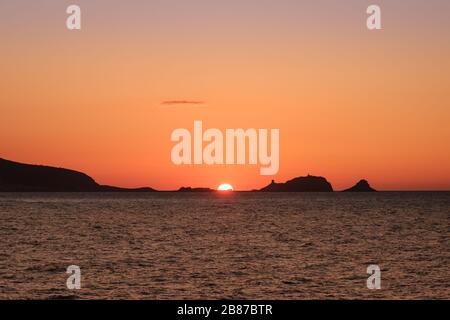 Sole dietro una 'la pietra' argentata, la roccia rossa a Ile Rousse nella regione Balagne della Corsica Foto Stock