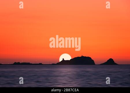 Sole dietro una 'la pietra' argentata, la roccia rossa a Ile Rousse nella regione Balagne della Corsica Foto Stock