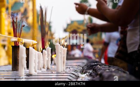 Bruciare candele e incenso in un colorato tempio buddista in Myanmar durante il giorno luce. Foto Stock