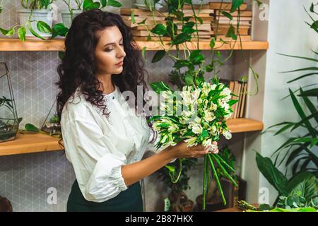 Attraente giovane donna fiorista sta lavorando in un negozio di fiori. Foto Stock