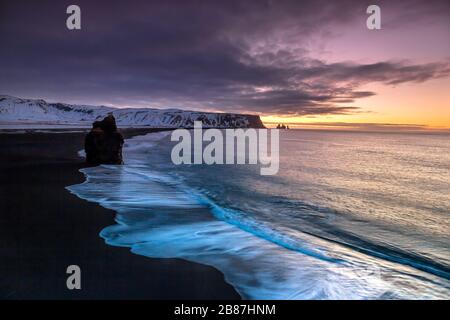 Reynisdrangar sono stacks di mare basalto situati sotto la montagna Reynisfjall vicino al villaggio Vík í Mýrdal, Islanda meridionale incorniciato da pile di basalto Foto Stock