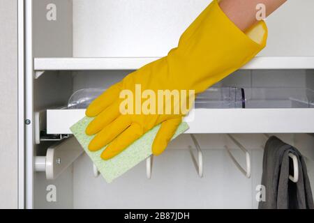 Il guanto di protezione in gomma con panno in microfibra sta pulendo un armadio in camera. Faccende domestiche. Сleaning o pulizia regolare. Foto Stock