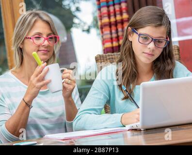 ragazza teen sorridente che fa i compiti con un insegnante biondo Foto Stock