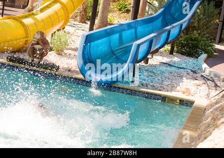 Fine dello scivolo d'acqua blu in piscina con spruzzi d'acqua Foto Stock