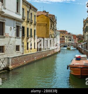 Venezia, Italia - 02 agosto 2019: uno delle migliaia di incantevoli angoli accoglienti a Venezia in una limpida giornata di sole. La gente del posto e i turisti passeggiano lungo il h Foto Stock