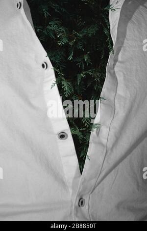 Ritratto surreale fotografia verde foglie sotto una camicia vestito bianco Foto Stock