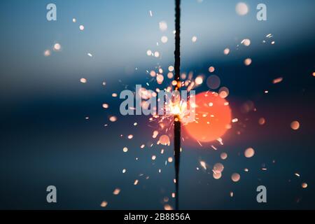 Illuminando fuori una festa di Sparkler di quattro luglio su una spiaggia al tramonto Foto Stock