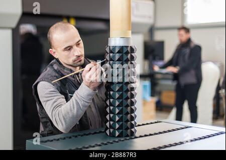 Tecnico addetto alla post-produzione, alla finitura e all'elaborazione del grande modello 3d stampato su una moderna stampante 3d con controllo computerizzato Foto Stock