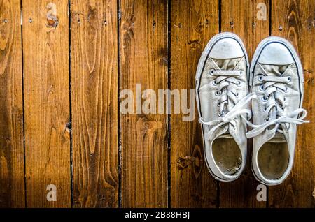 Sneakers bianche in tela da donna su pavimenti in legno duro Foto Stock