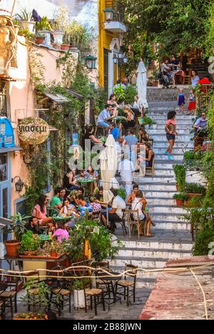 Persone che cenano fuori sulle scale nel quartiere Plaka di Atene. Foto Stock