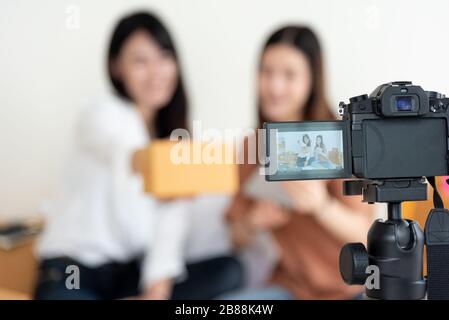 Primo piano della videocamera digitale che registra due ragazze che presentano la pubblicità di nuovo prodotto. Concetto di vlog e influencer. Persone lavoro part-time e occupi Foto Stock