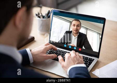 Visualizzazione dello schermo del PC sulla spalla dell'uomo d'affari durante il processo di trattative remote Foto Stock