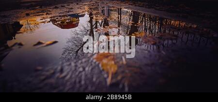 Riflessioni in pozzanghere o lago di edifici, barca o alberi e lampade da strada. Foto Stock