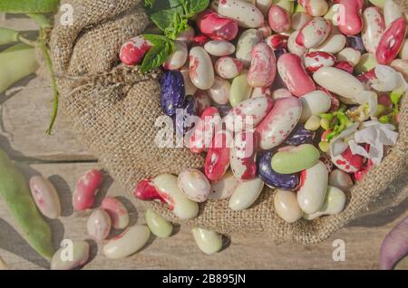 Sacco di mescolare fagioli versare i fagioli con fagioli sul tavolo di legno. Fagioli di Lima in sacchetto di tela su sfondo di legno. Foto Stock