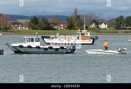 Traghetto che traina una barca rotta nel porto di Chichester vicino a Itchenor, West Sussex, Regno Unito Foto Stock