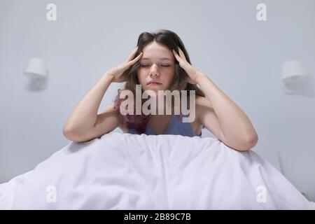 Triste adolescente ragazza seduta a casa a letto. Foto Stock